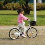 Fetiță care merge pe bicicletă prin parc