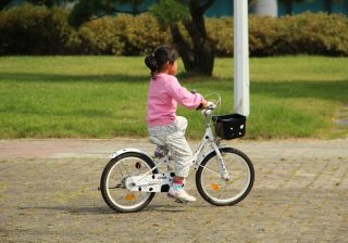 Fetiță care merge pe bicicletă prin parc