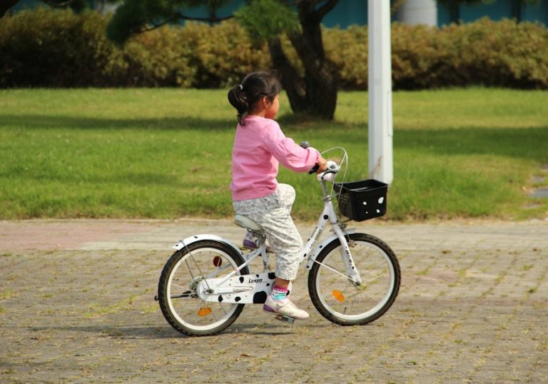 Fetiță care merge pe bicicletă prin parc