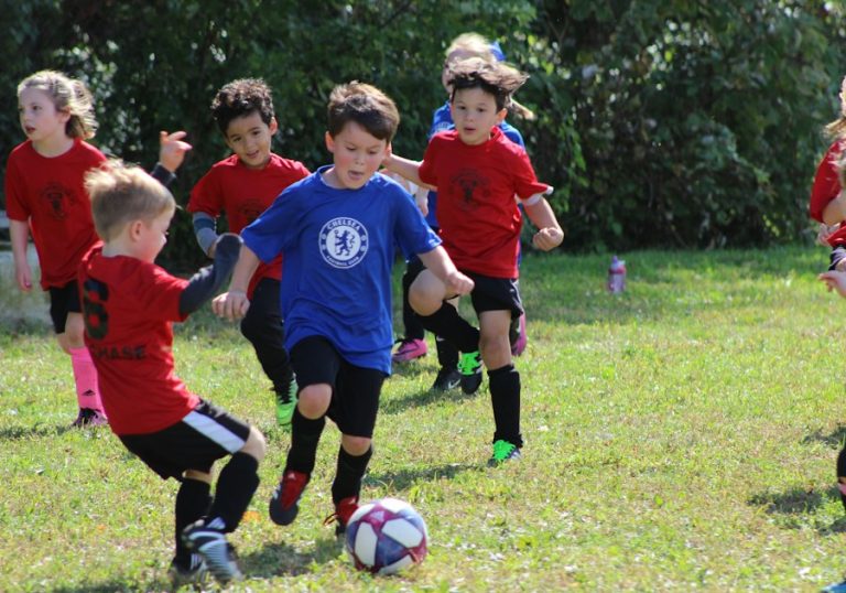 Copii care joacă fotbal pe gazon, într-un meci între echipe de juniori