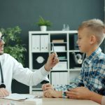Medic care discută cu un băiat și cu mama lui în cabinet