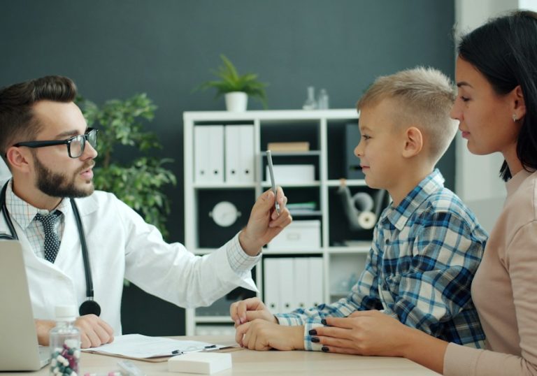 Medic care discută cu un băiat și cu mama lui în cabinet